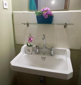 La salle de bains est pourvue d'un lavabo blanc et de fleurs. dans l'établissement Zeta's vintage garden house, à Sparte