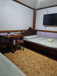 Habitación con 2 camas, mesa y TV. en Family Room in Bato, Camarines Sur 