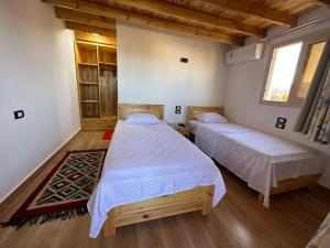 2 łóżka w pokoju z drewnianą podłogą w obiekcie Beit Tolba w mieście Dahab