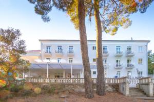 a large white building with trees in the foreground at Hotel Bor in Krk