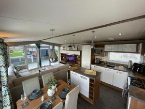 a kitchen and living room with a couch and a table at Golden Anchor - The Milano - Coastal Caravan Breaks in Chapel Saint Leonards