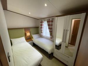 a small bedroom with two beds and a mirror at Golden Anchor - The Milano - Coastal Caravan Breaks in Chapel Saint Leonards +12 photos