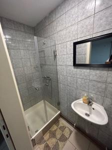 a bathroom with a shower and a sink and a mirror at Apartman Vanja in Požega
