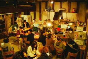 un grupo de personas sentadas alrededor de un bar en Hostel&Bar CAMOSIBA, en Yokote