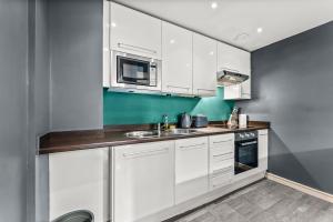 una cocina con armarios blancos y fregadero en Spacious Central Manchester Apartment - Sleeps 8 en Mánchester