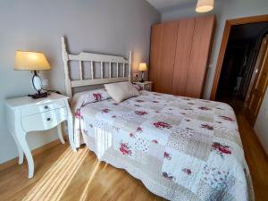 1 dormitorio con 1 cama y mesita de noche con colcha blanca en Apart. Casa Juaneta Pirineo-Ordesa, en Broto