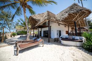 un complejo en la playa con camas y palmeras en Beachfront Villa Patti ZanzibarHouses, en Kiwengwa