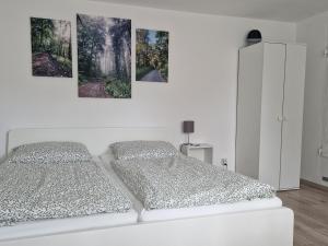 a bedroom with two beds and three paintings on the wall at Waldbergperle Ernsbach in Forchtenberg