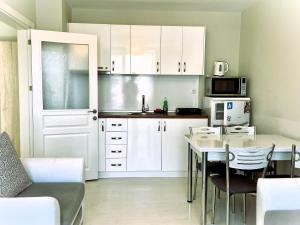 een keuken met witte kasten en een tafel met stoelen bij Apartments Stamopolu Lux with pool view in Primorsko