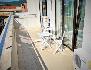 a balcony with two chairs and a table on a building at Apartments Stamopolu Lux with pool view in Primorsko