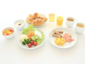 una mesa blanca con platos de comida y bebida en Smile Hotel Kumagaya, en Kumagaya