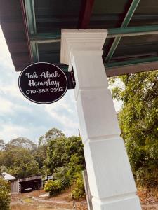 Tok Abah Homestay Bukit Mertajam في بوكيت ميرتاجام: علامة على جانب منزل مع عامود