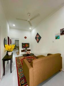 Tok Abah Homestay Bukit Mertajam في بوكيت ميرتاجام: غرفة معيشة مع أريكة وتلفزيون