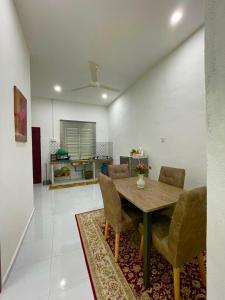 Tok Abah Homestay Bukit Mertajam في بوكيت ميرتاجام: غرفة معيشة مع طاولة وكراسي خشبية