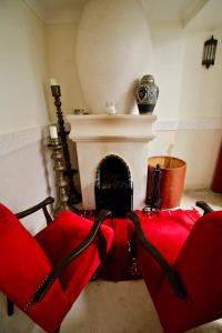 a living room with a red couch and a fireplace at Riad Karmela in Marrakesh