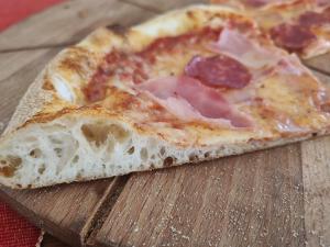 una rebanada de pizza sobre una mesa de madera en Pensiunea Daria, en Fundata