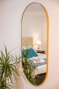 ein Spiegel, der ein Schlafzimmer mit einem Bett und einem Stuhl reflektiert in der Unterkunft Villa Turquesa Estoril in Alcabideche
