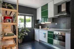 una cocina con armarios verdes y blancos y fregadero en Villa Turquesa Estoril, en Alcabideche
