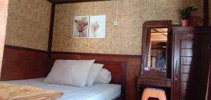 a bedroom with a bed with a wooden headboard and a mirror at Radiya Guesthouse in Sembalun Lawang