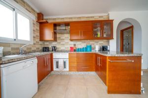 a kitchen with wooden cabinets and a white dishwasher at CASA DIEGO PUERTO BLANQUILLO in Frigiliana