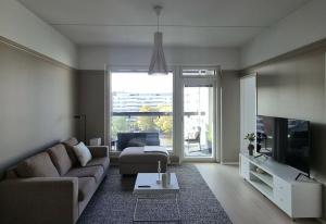 ein Wohnzimmer mit einem Sofa und einem TV in der Unterkunft Hotellitasoinen, uusi huoneisto! in Tampere