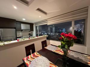 a kitchen with a table with a vase of red roses at Five Stars Suites - Park - Quito in Quito