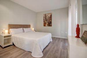 a white bedroom with a white bed and a window at Beds & Breaks Casals in Valencia