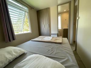 two beds in a room with a window at Mobilehome lumineux 2 chambres - 4 personnes - Proche Europa Park in Boofzheim