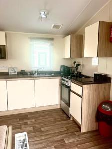 a kitchen with white cabinets and a stove top oven at 6 Birth Caravan Ingoldmels in Ingoldmells