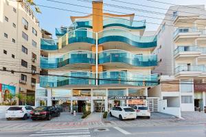 ein Gebäude mit davor geparkten Autos in der Unterkunft 1054 - Apartamento Centro de Bombinhas - Vista Mar - 1 Vaga Garagem - 50 metros Praia in Bombinhas