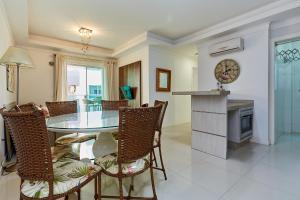 ein Esszimmer mit Glastisch und Stühlen in der Unterkunft 1054 - Apartamento Centro de Bombinhas - Vista Mar - 1 Vaga Garagem - 50 metros Praia in Bombinhas