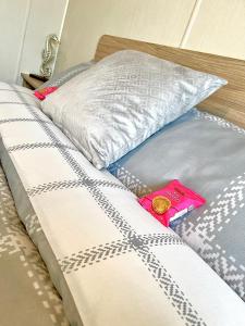a bed with a pillow and a pink packet on it at 6 Birth Caravan Ingoldmels in Ingoldmells