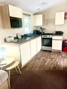 a kitchen with white cabinets and a wooden floor at 6 Birth Caravan Ingoldmels in Ingoldmells