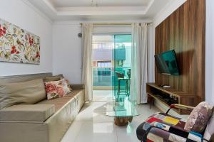 ein Wohnzimmer mit Sofa und Fernseher in der Unterkunft 1054 - Apartamento Centro de Bombinhas - Vista Mar - 1 Vaga Garagem - 50 metros Praia in Bombinhas