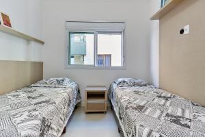 zwei Betten in einem Zimmer mit Fenster in der Unterkunft 1054 - Apartamento Centro de Bombinhas - Vista Mar - 1 Vaga Garagem - 50 metros Praia in Bombinhas