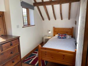a bedroom with a bed and a dresser in a room at Annex at Southfields in idyllic Hampshire village in Greywell