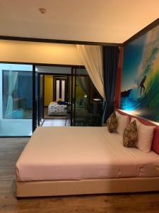 a bedroom with a large bed with a painting on the wall at Must Sea Hotel - SHA Hotel in Kata Beach