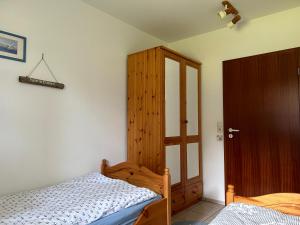 1 dormitorio con 1 cama y armario de madera en Ferienwohnung Moby Dick, en Ording