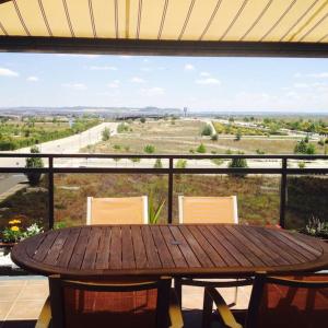 a wooden table and chairs on a balcony with a view at Atico, Piscina, AC, WI-FI y Parking Gratis, Gran Terraza, VUT 47-79 in Arroyo de la Encomienda