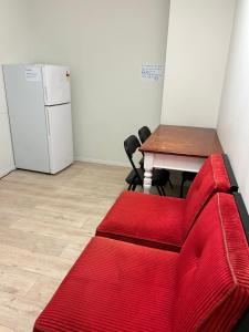 a red couch in a room with a table and a refrigerator at Sky World Cozy Home in Auckland