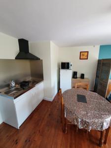 eine Küche und ein Esszimmer mit einem Tisch und einem Kühlschrank in der Unterkunft Studio cosy de Rochavelle in Chiché