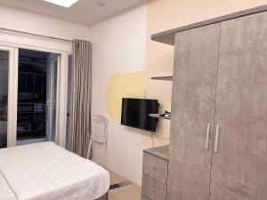 1 dormitorio con 1 cama y armario con TV en Moka's House en Ho Chi Minh