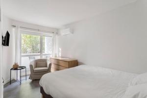 1 dormitorio con 1 cama, 1 silla y 1 ventana en Le Roucas - Chaleureux appartement aux Baux de Provence en Les Baux-de-Provence