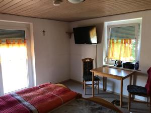 a bedroom with a bed and a desk and a tv at Pension Grüner Baum 