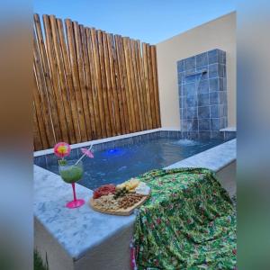 a table with a tray of food next to a swimming pool at Marinho Suítes Milagres in São Miguel dos Milagres