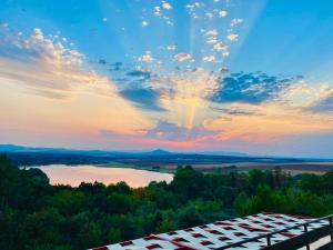 Blick auf den Sonnenuntergang über einem See und einem Gebäude in der Unterkunft Хижа Манастирчето-Книжовник in Chaskowo