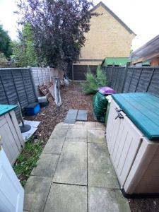 a backyard with a wooden fence and a sidewalk at Entire 1 bedroom city house in London