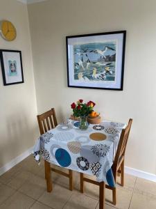 a dining room table with a vase of flowers on it at Da Peerie Hoose in Hamnavoe