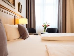 una habitación de hotel con una cama y un jarrón de flores en Hotel Lindenufer, en Berlín