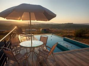 a table with chairs and an umbrella next to a pool at Casa com piscina Capitólio in Capitólio